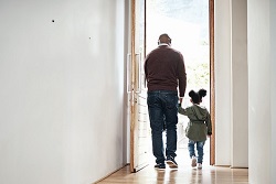 Older man walking out door with little girl