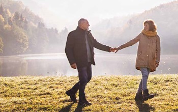 man and woman walking near lake