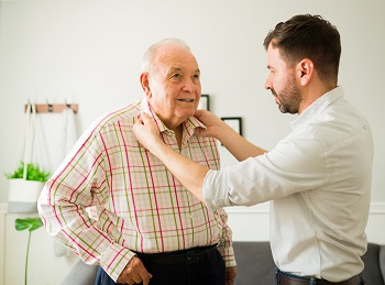 Man helping older man with shirt collar