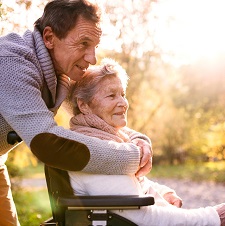 woman in wheelchair with man behind her